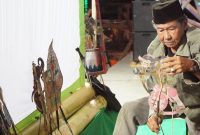 Kai Umpok menyusun wayang kulit di atas panggung sebelum tampil