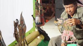 Kai Umpok menyusun wayang kulit di atas panggung sebelum tampil