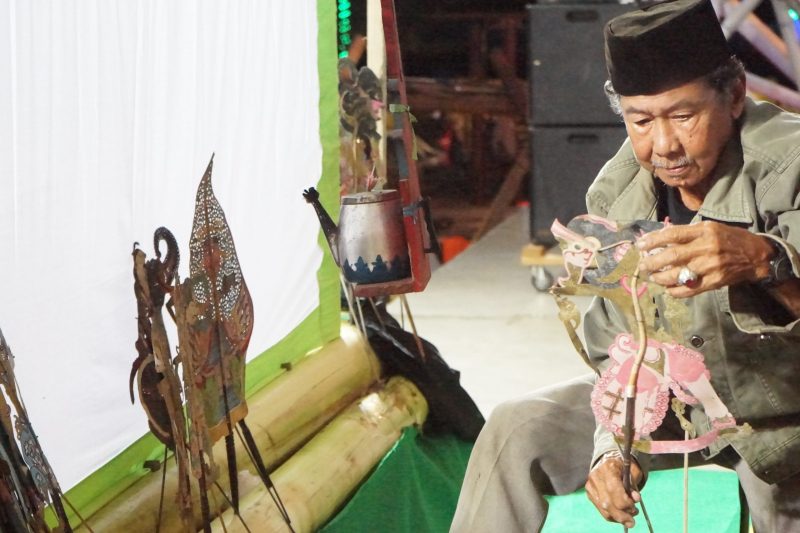 Kai Umpok menyusun wayang kulit di atas panggung sebelum tampil